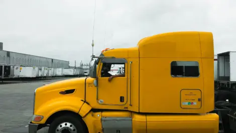 Bright yellow semi-truck cab parked in an industrial lot.