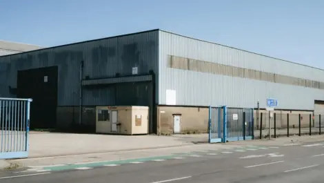 Industrial warehouse with blue gates and small guard cabin.