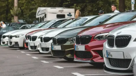 Line of parked BMW cars in various colors at an outdoor lot.