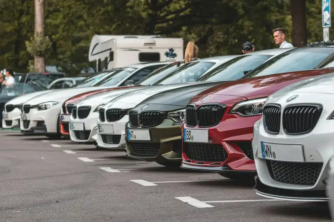Line of parked BMW cars in various colors at an outdoor lot.