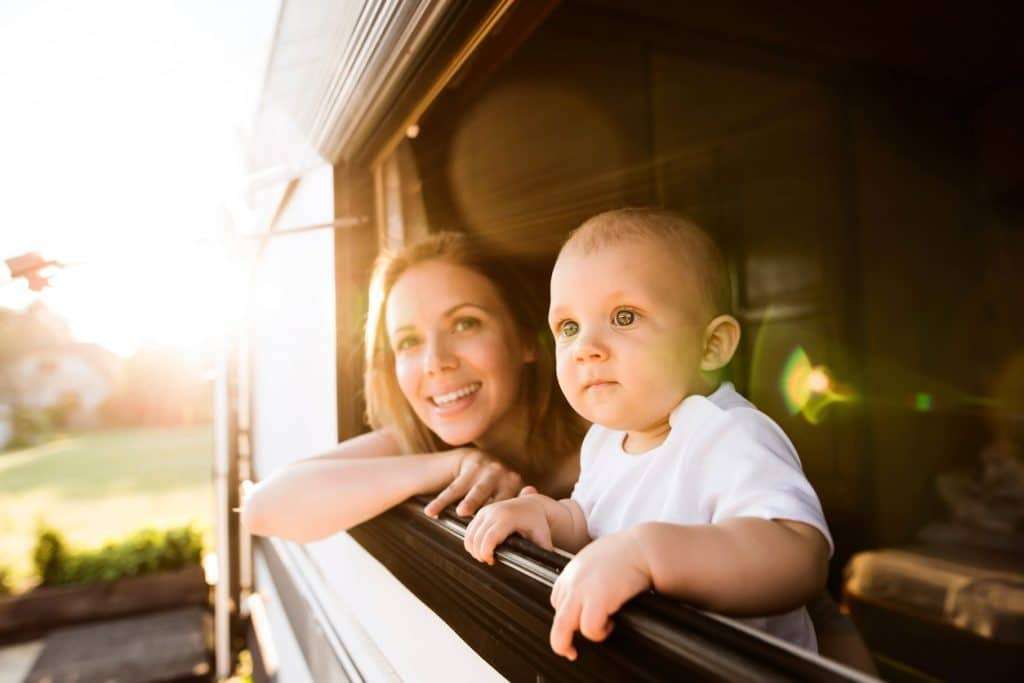 A mom and baby look out the window of an RV.