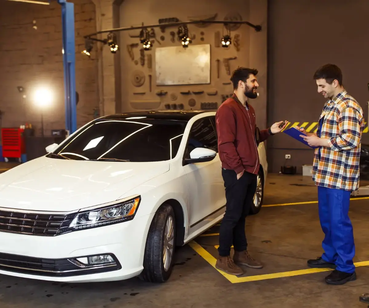 Man discussing car insurance details with a technician.