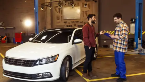 Man discussing car insurance details with a technician.