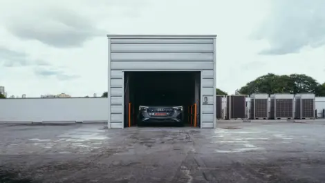 Classic car parked inside outdoor storage unit with roll-up door open.