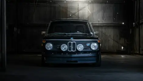 Black BMW inside secure indoor vehicle storage facility.