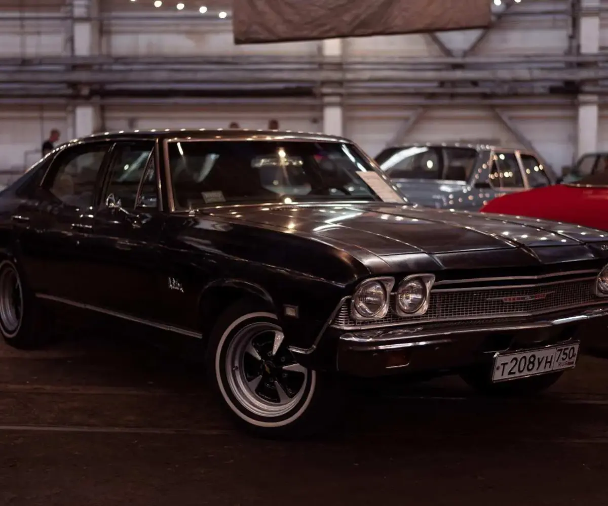 Black classic car displayed indoors at a vintage car exhibition.