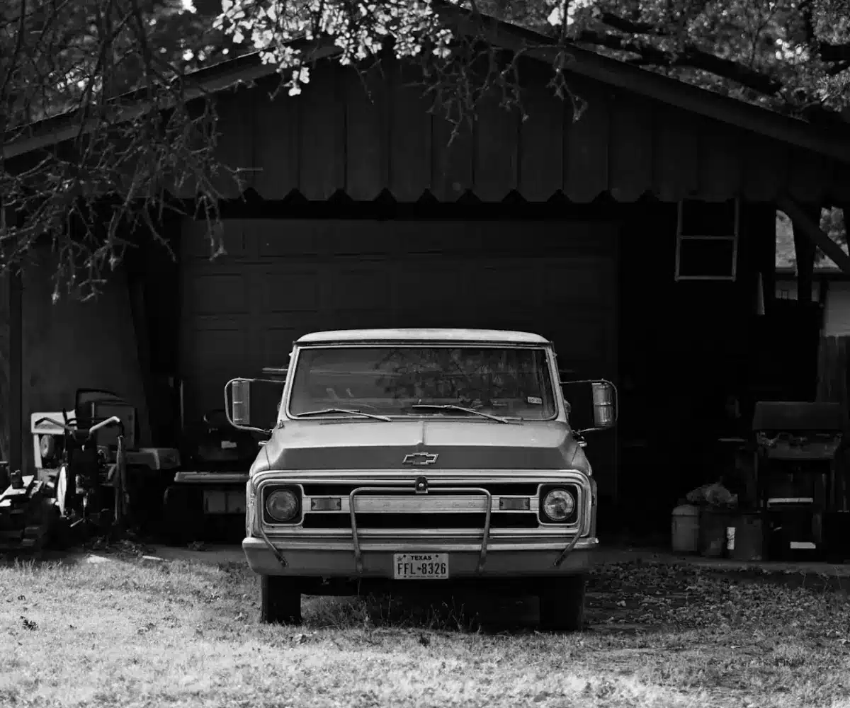 Vintage pickup truck parked in covered outdoor car storage shed.