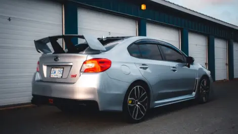 Silver sports sedan parked outside a row of storage garage units