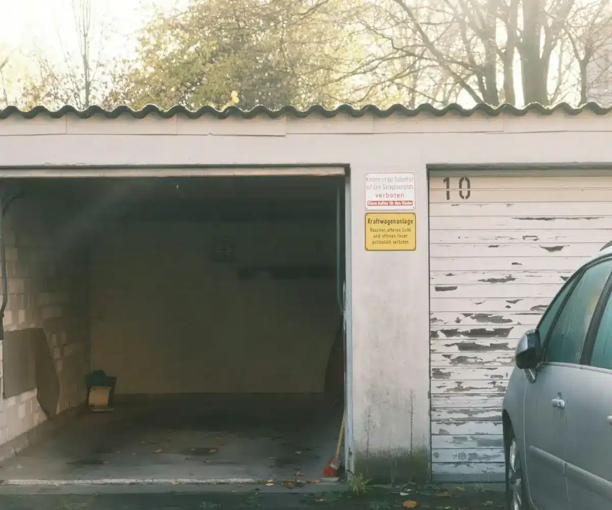 Residential garage with an empty interior next to a parked car outside
