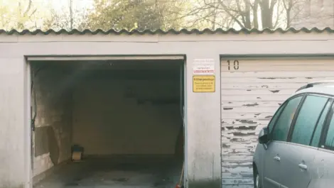 Residential garage with an empty interior next to a parked car outside