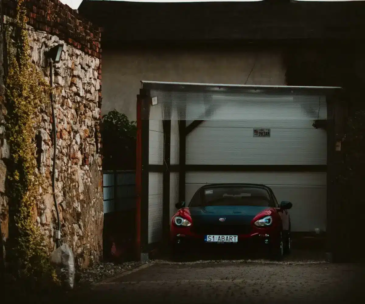 Red sports car parked inside secure indoor garage storage unit.