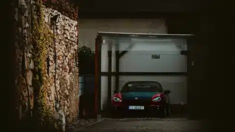 Red sports car parked inside secure indoor garage storage unit.