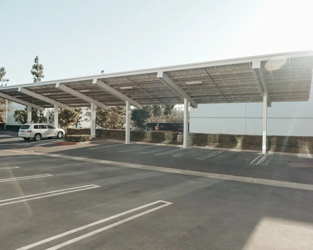 Covered outdoor parking structure with solar panel roofing and parked cars, illustrating a sheltered alternative to street parking.