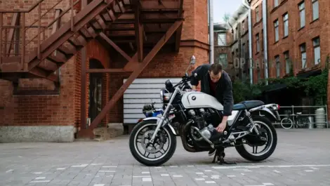Motorcycle owner checking and maintaining a bike in an outdoor setting, highlighting ownership, upkeep, and long-term care.