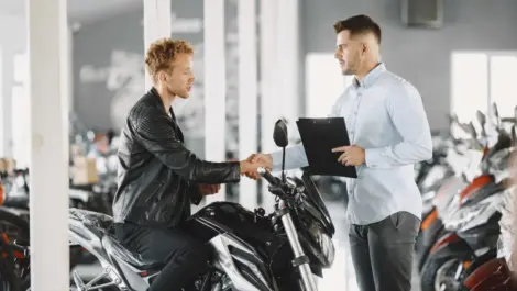 Buyer and seller discussing a motorcycle purchase with documents, highlighting ownership, registration, and legal considerations.