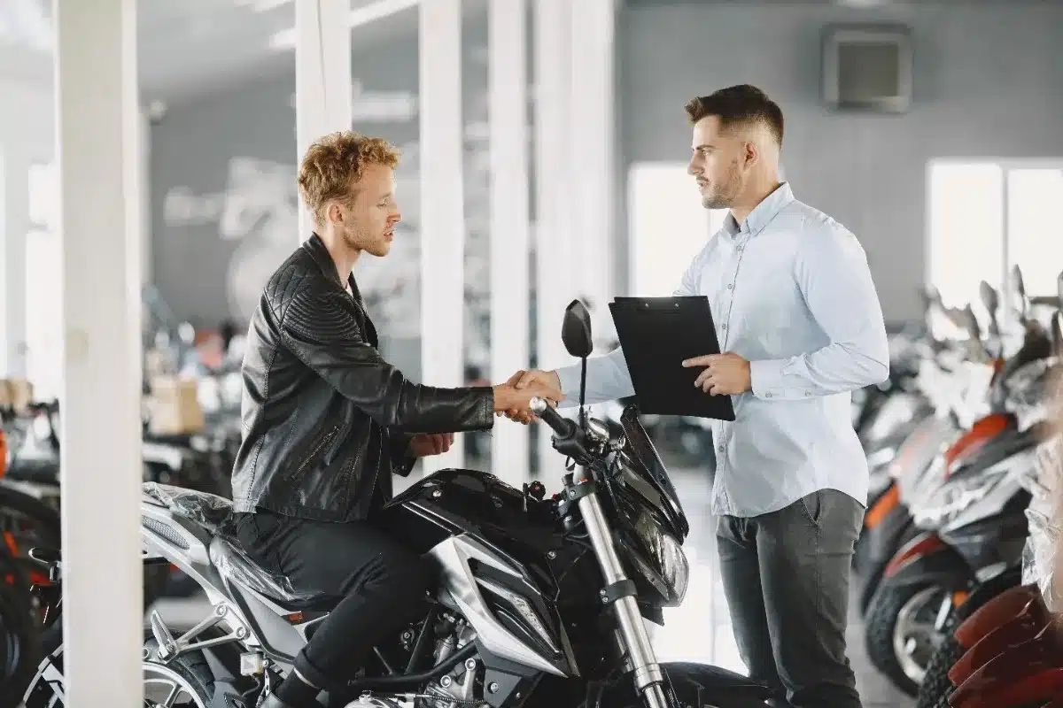 Buyer and seller discussing a motorcycle purchase with documents, highlighting ownership, registration, and legal considerations.