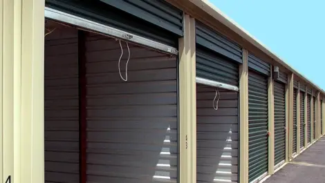Row of enclosed self-storage units with metal roll-up doors at a storage facility