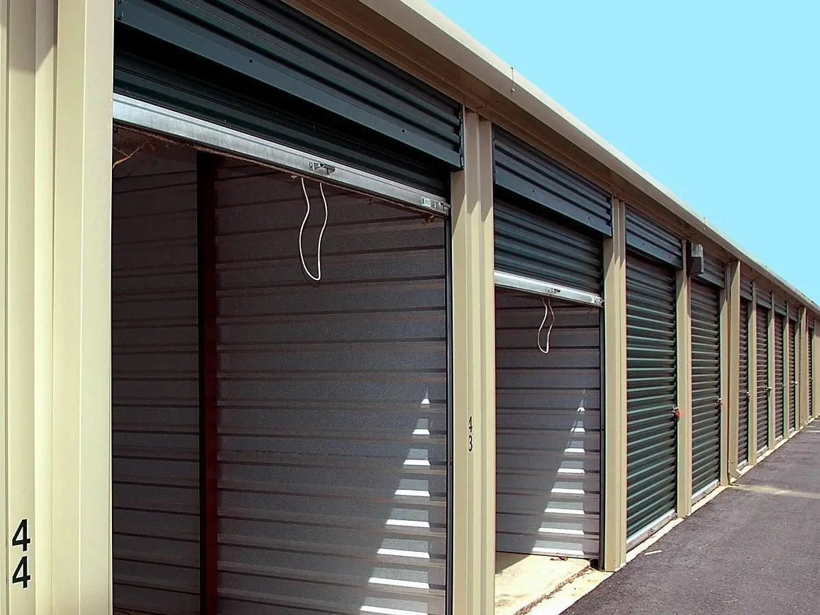 Row of enclosed self-storage units with metal roll-up doors at a storage facility