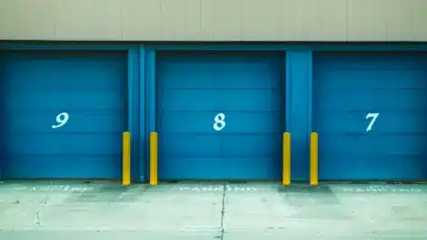 Storage facility with blue roll-up doors and concrete driveway.