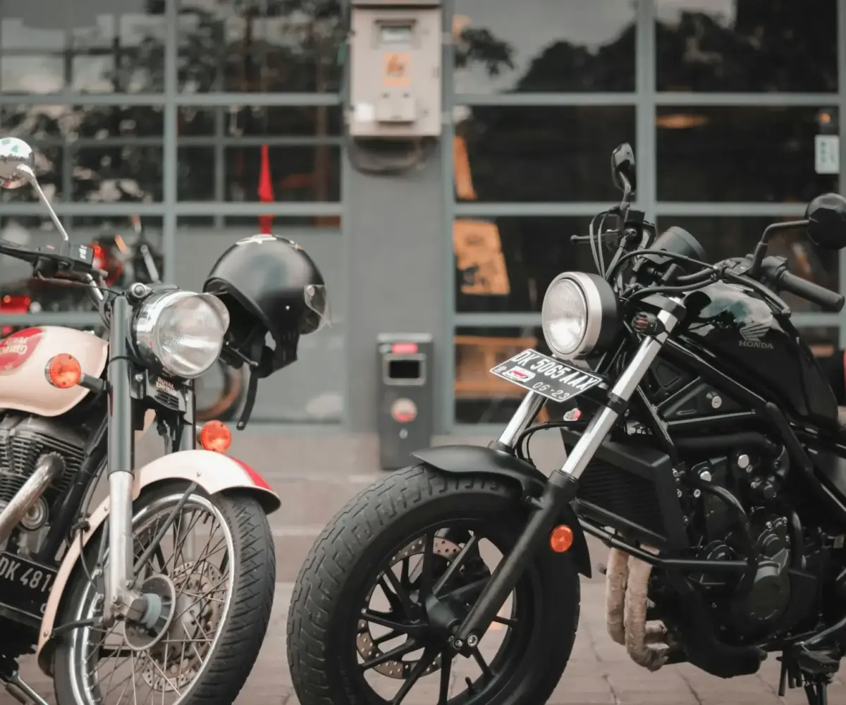 Motorcycles parked outdoors near a garage, illustrating typical ownership conditions where space, weather, and security can drive the need for storage.