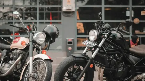 Motorcycles parked outdoors near a garage, illustrating typical ownership conditions where space, weather, and security can drive the need for storage.