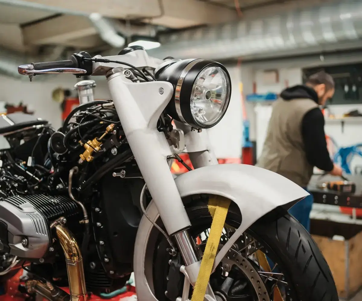 Technicians working on a motorcycle in a garage, highlighting maintenance and preparation needed before storing a bike long term.