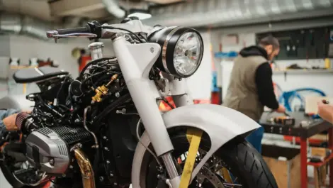 Technicians working on a motorcycle in a garage, highlighting maintenance and preparation needed before storing a bike long term.