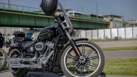 Motorcycle parked outdoors near a roadside with no cover, illustrating exposure to weather and the need for proper protection during outdoor storage.