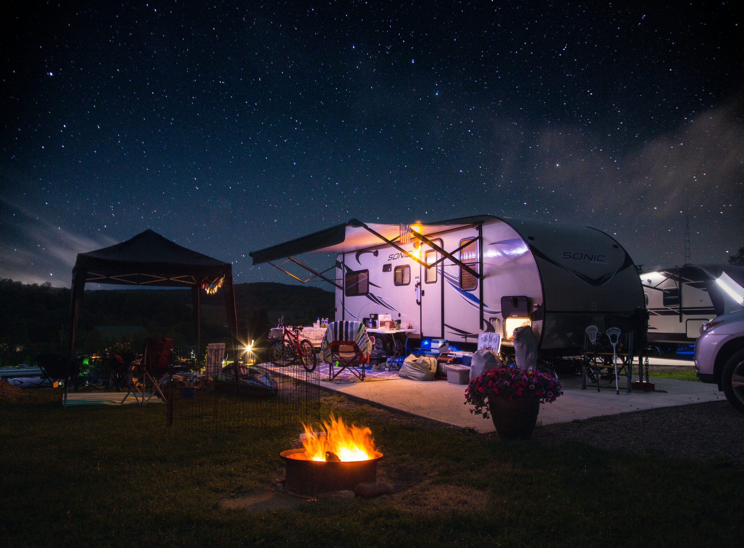 Travel trailer set up at a campsite under a star-filled night sky, illustrating RV camping adventures at some of the best state parks in Texas.